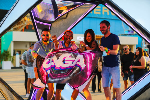 Four happy adults holding a large metallic balloon with the text 