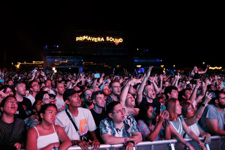 A large, enthusiastic crowd at the Primavera Sound festival at night, with many people cheering, taking photos, and watching a performance.