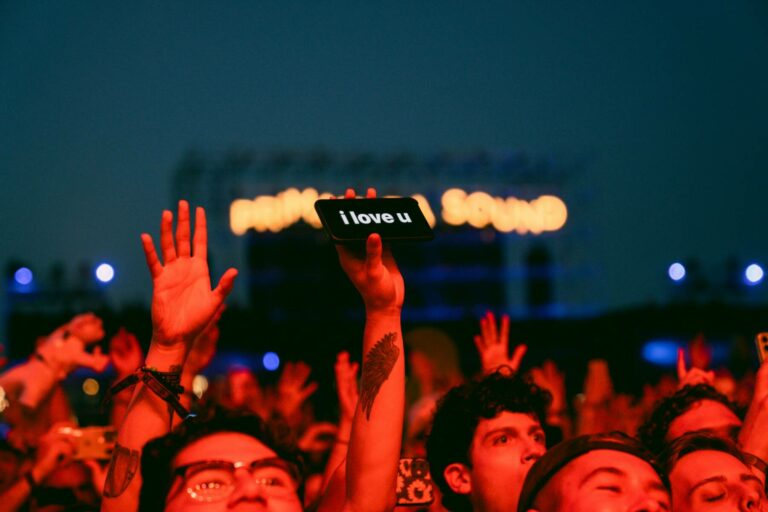A crowd at a concert with a person holding up a smartphone displaying the message 