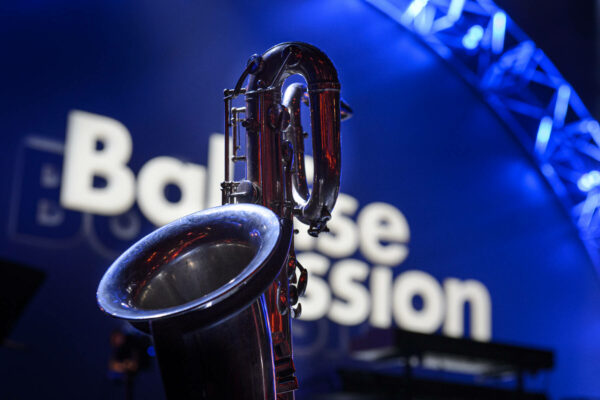 A saxophone in sharp focus against a blurred background with the illuminated words 