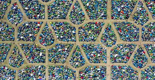 Aerial view of a densely packed festival camping area with colorful tents arranged in geometric patterns separated by walkways.