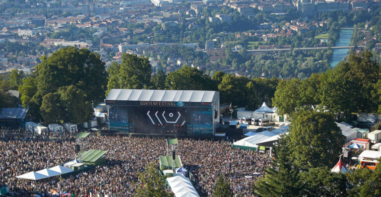 Aerial view of a crowded music festival with a large stage displaying 
