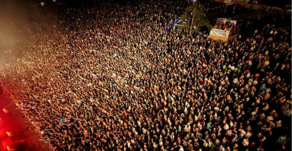 Aerial view of a densely packed crowd at an outdoor event during the evening.