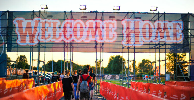 A group of people walking towards a large entry gate with the words 