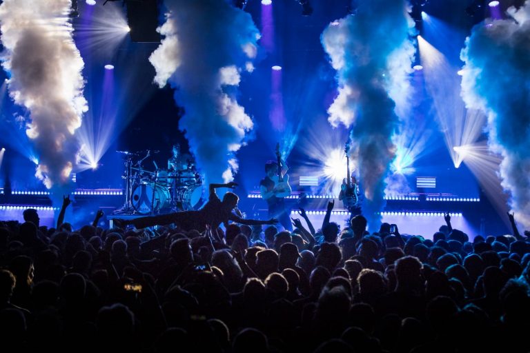 A concert scene with silhouettes of musicians on stage and the excited crowd below, with dynamic stage lighting and smoke effects creating a vibrant atmosphere.