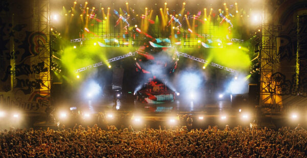 A concert stage with vibrant lighting and a large crowd of spectators enjoying the performance.
