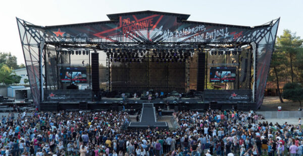 A large outdoor music festival stage with a banner reading 