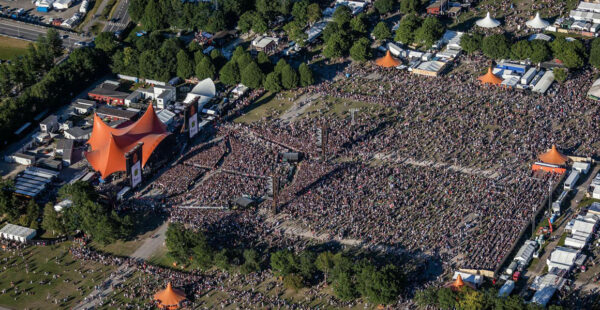 Aerial view of a large outdoor music festival with multiple stages and a huge crowd of attendees.