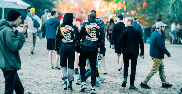 A group of people walking at an outdoor event with two individuals in matching jackets with 