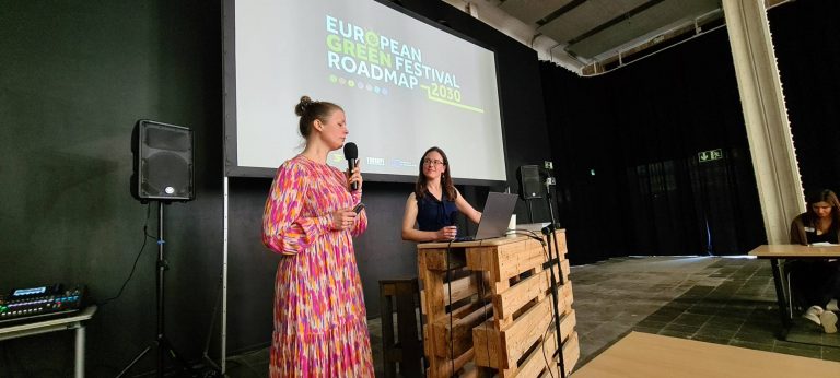 Two women presenting at an indoor event with a projection screen displaying "EUROPEAN GREEN FESTIVAL ROADMAP 2030" in the background.