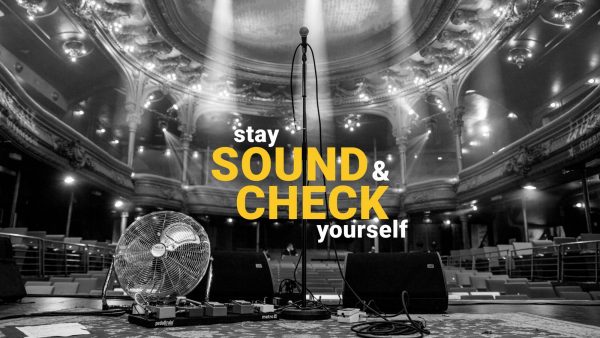 A black and white photo of a theater stage with a microphone stand at the center, surrounded by stage equipment and a fan; the words 'stay SOUND & CHECK yourself' are overlaid in bold yellow and white text.