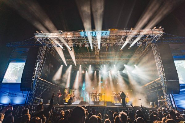 Outdoor concert stage with bright spotlights and a crowd watching a live band at night during ELBJAZZ festival.
