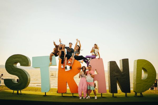 Group of people posing and sitting on large colorful letters spelling 