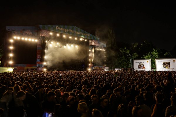 Large crowd gathered at night in front of an illuminated stage at the Orange Warsaw Festival outdoor concert.