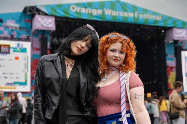 Two women posing at an outdoor music festival stage with 