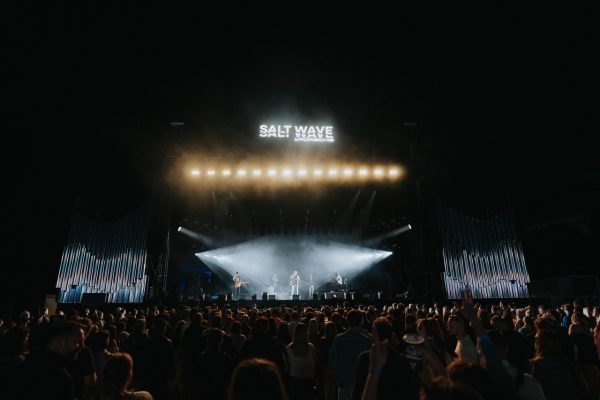 Crowd watching a live band performing on stage illuminated by bright lights with 