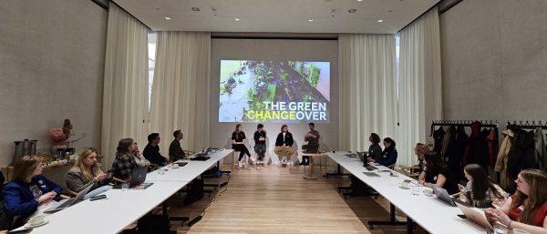 Panel discussion with four speakers seated in front of a projected slide titled 