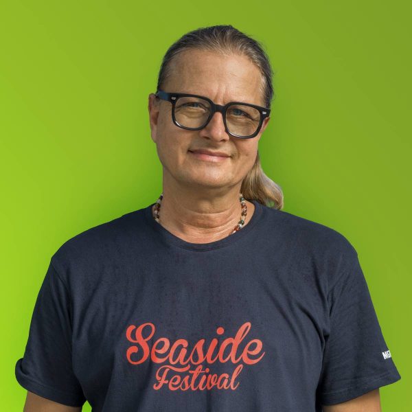 Middle-aged person with long hair wearing large black glasses, a black 